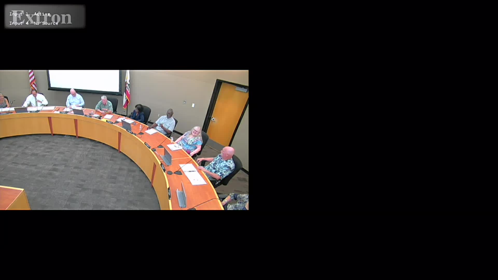 A graphic announcing a Planning Commission Meeting for the City of Tracy. The background shows a soft-focus image of a busy street, lined with arts and crafts vendors. At the top is the City of Tracy logo with stylized green and brown lines. To the right is a QR code labeled “Scan for Meeting Agenda.” In the center, large text reads “City of Tracy Planning Commission Meeting.” A green banner at the bottom displays the date and time: “April 8, 2026, at 7:00 p.m.”